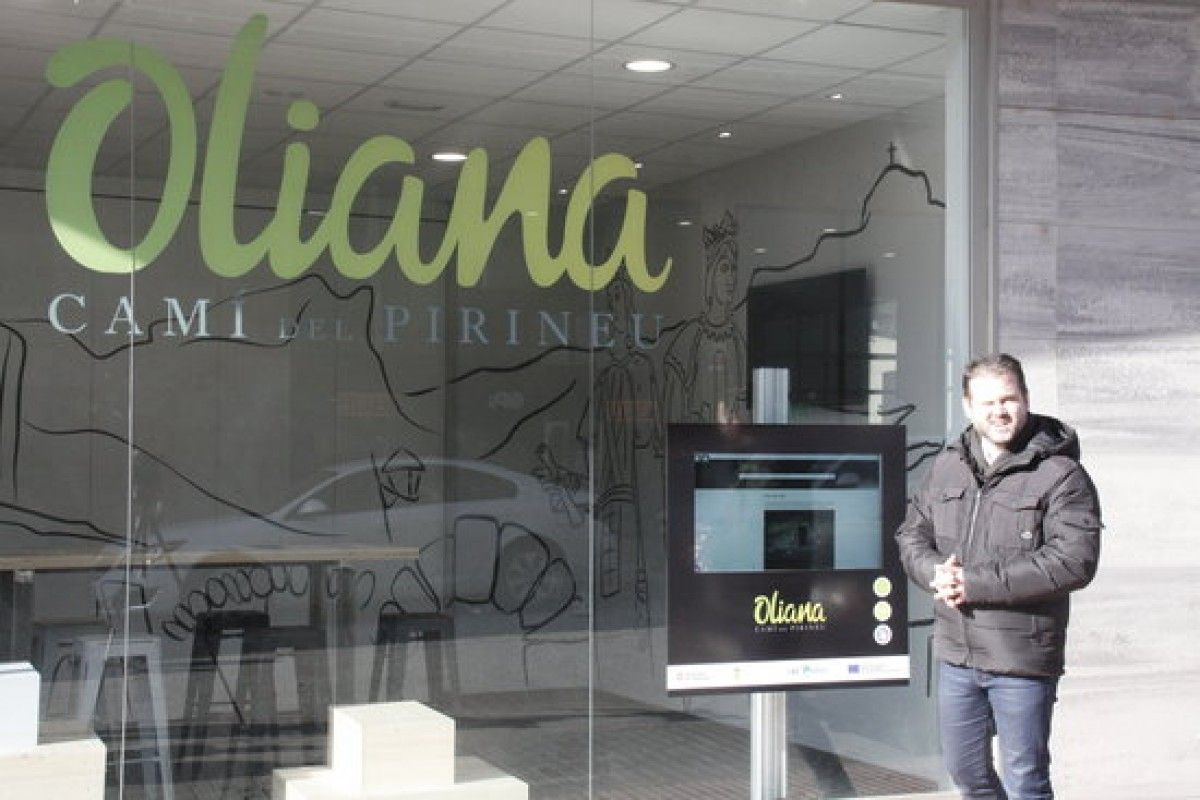 A la dreta de la imatge el regidor de turisme d'Oliana, Ricard Pérez, davant de l'oficina de turisme, on es pot veure la nova marca i la pantalla tàctil disponible les 24 hores