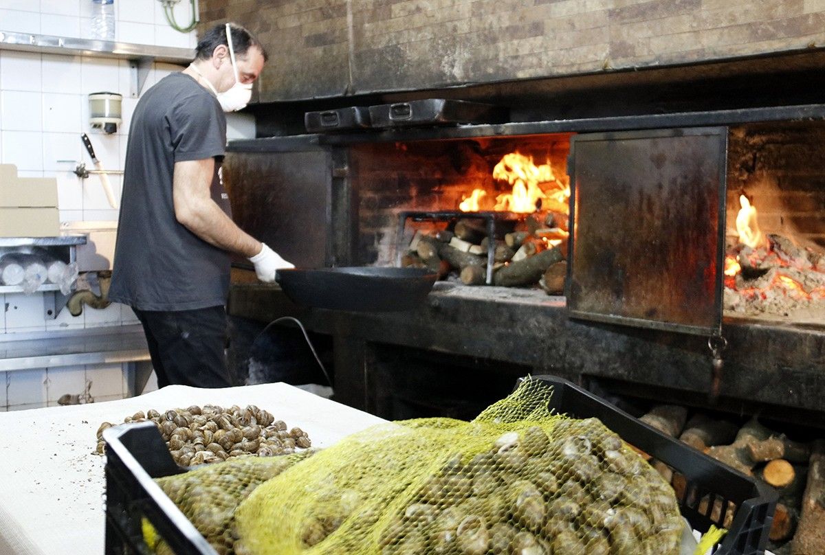 Un dels treballadors del restaurant La Dolceta de Lleida prepara el foc per fer el menjar que serviran a domicili, amb els caragols en primer terme.