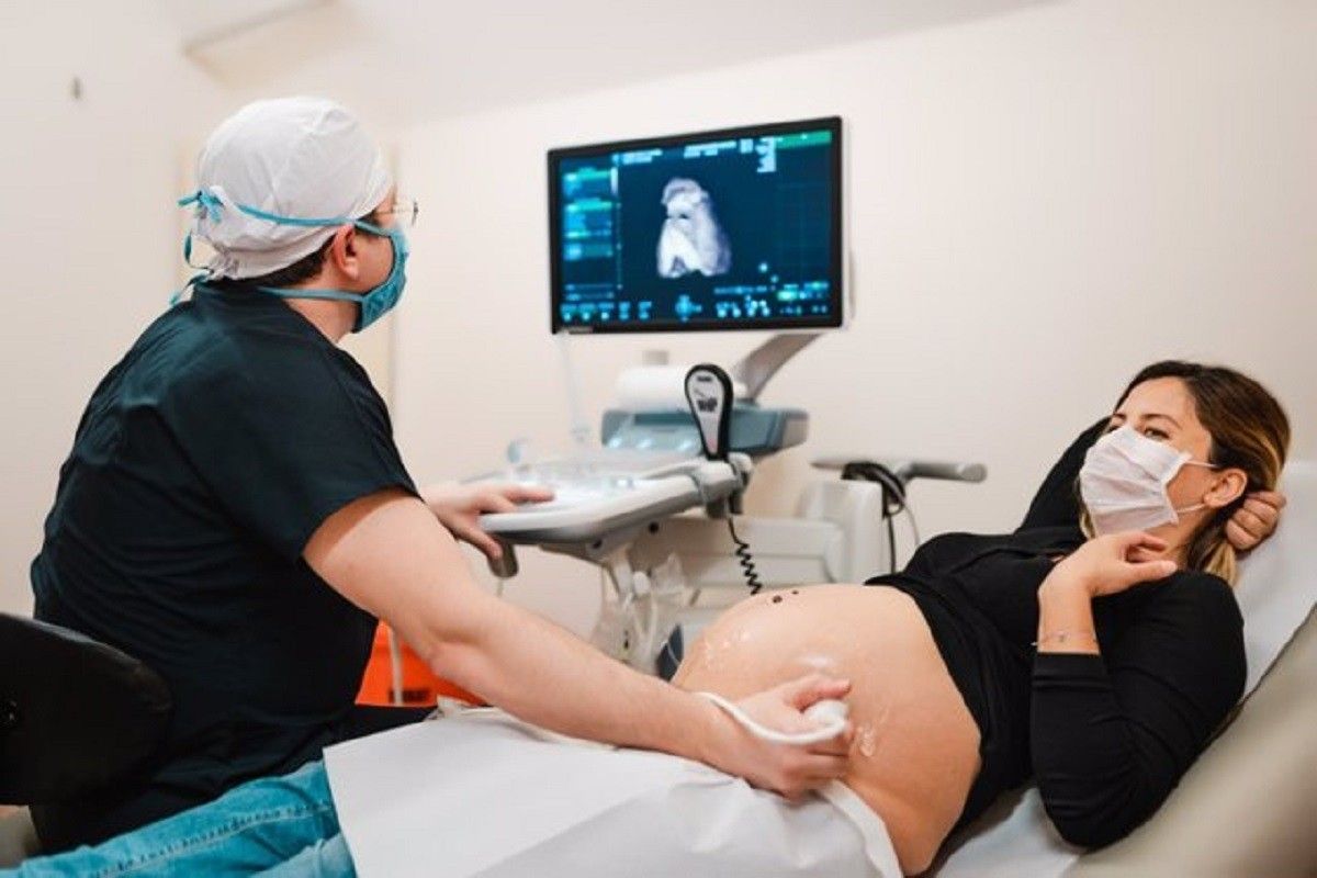 Una dona embarassada fent-se una ecografia amb mascareta.