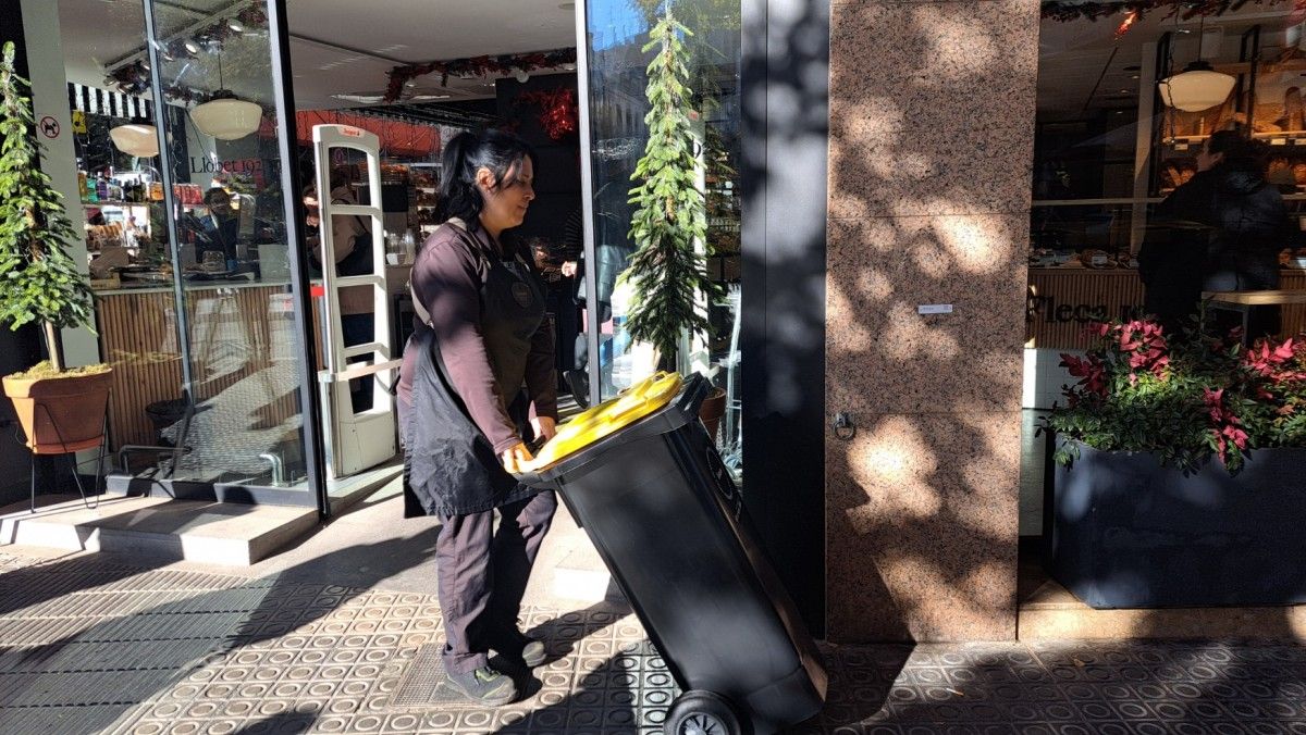 La treballadora d'un supermercat treu un contenidor d'envasos al carrer