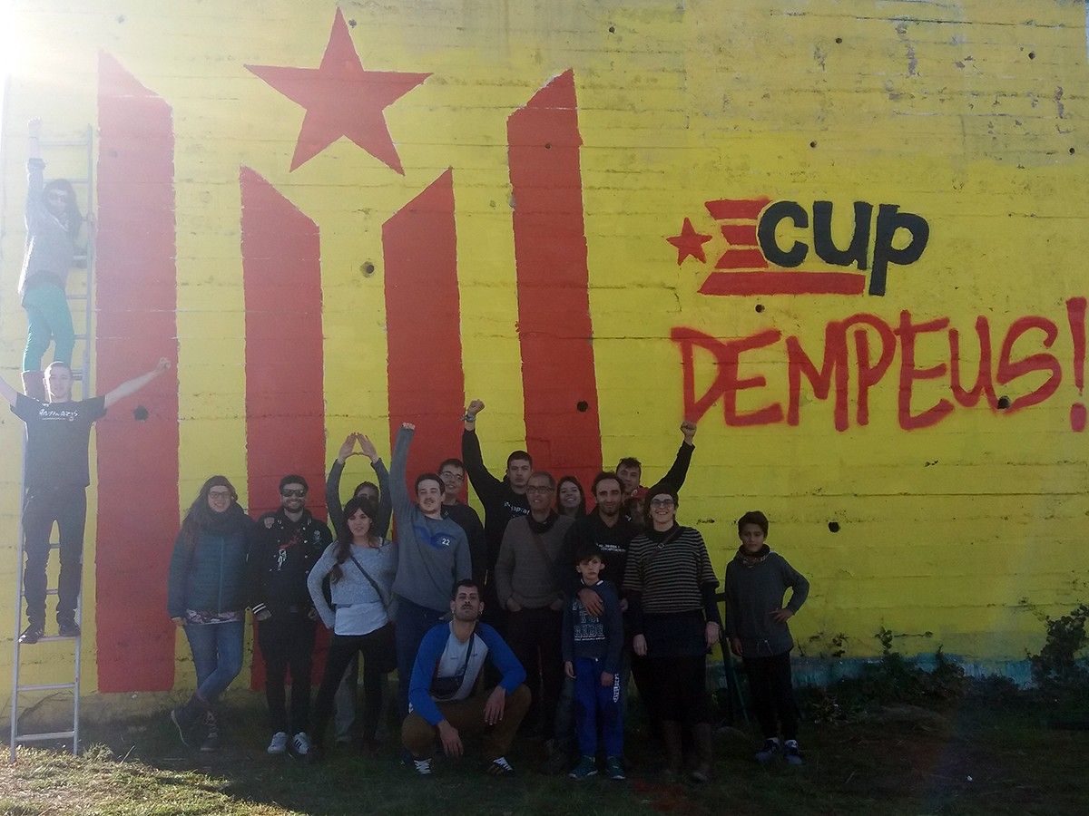 Militants de la CUP amb el mural repintat de la Catalana