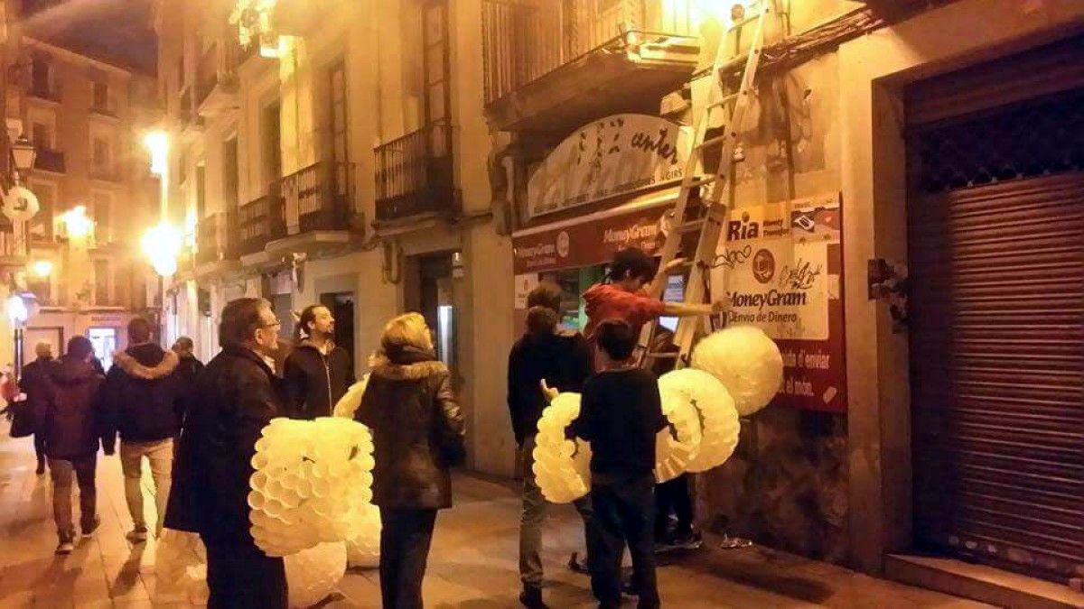 Comerciants i voluntaris coloquen els llums de Nadal al carrer Vilanova