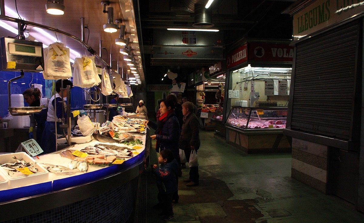 Pla general del Mercat Puigmercadal amb algunes botigues obertes i d'altres amb la persiana baixada