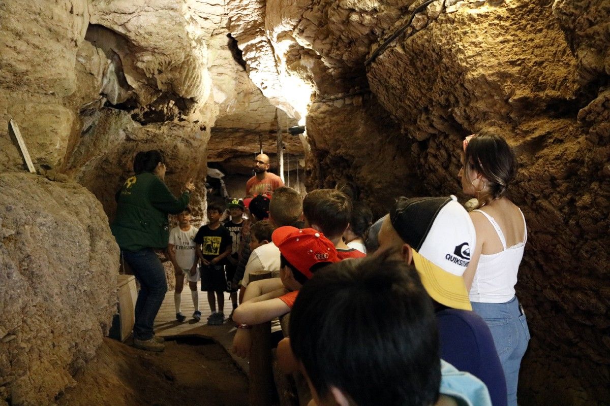 Un grup d'alumnes escoltant atentament les explicacions de la visita guiada per dins la Cova del Toll de Moià