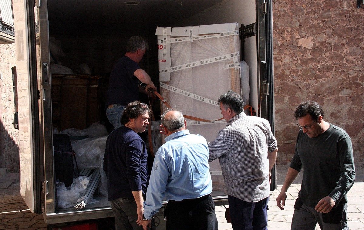 Diverses persones ajuden a descarregar del camió les peces que conformen el retaule del Roser de Salelles després d'haver estat restaurat