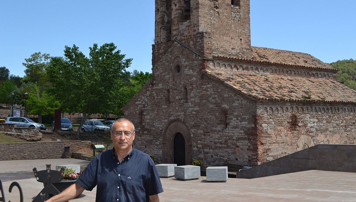 L'alcalde de Castellnou de Bages, Domènec Òrrit, amb l'església de Sant Andreu al fons