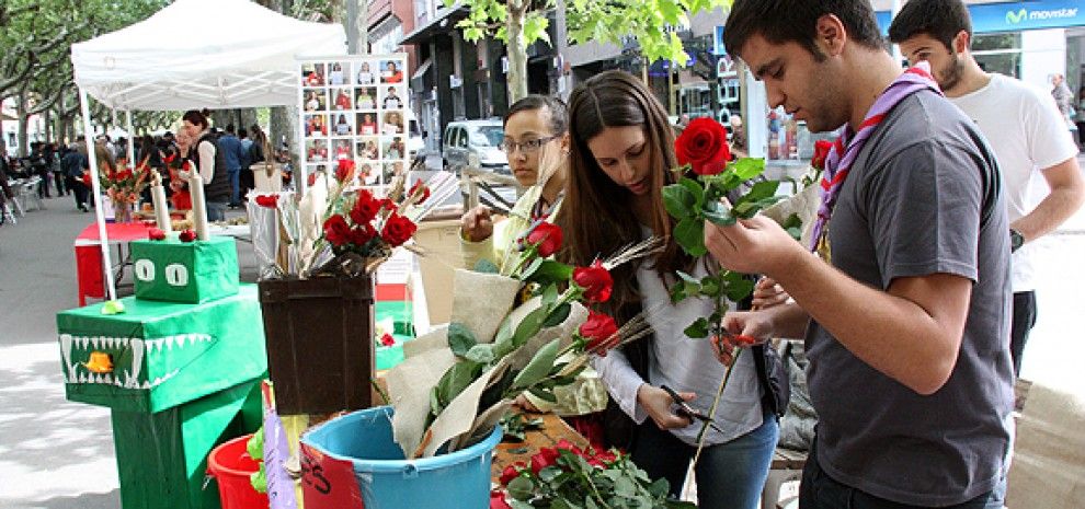 Uns joves embolcallen les roses que venen a la seva parada, aquest dijous al Passeig Pere III.