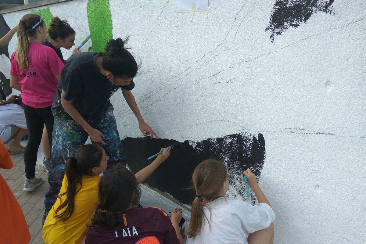 Infants i joves pintant el mur del pavelló de Sant Fruitós