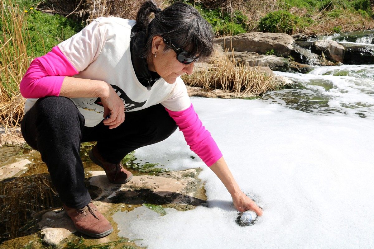 Una membre del grup A Contracorrent omple una ampolla d'aigua del riu contaminat