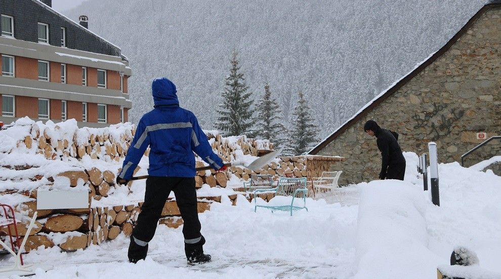 Dues persones traient la neu d'una terrassa a Vaquèira