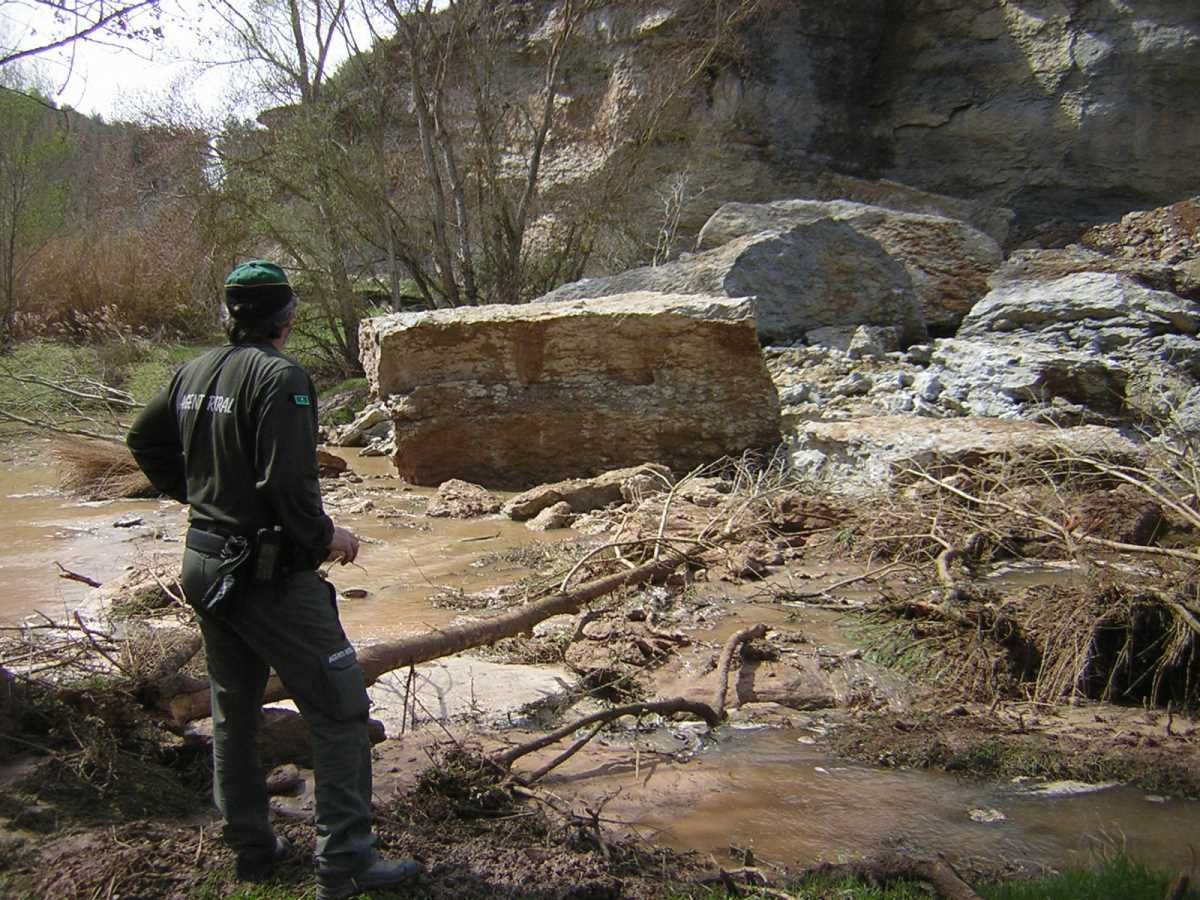 Un agent rural es mira les immenses roques que han caigut al riu