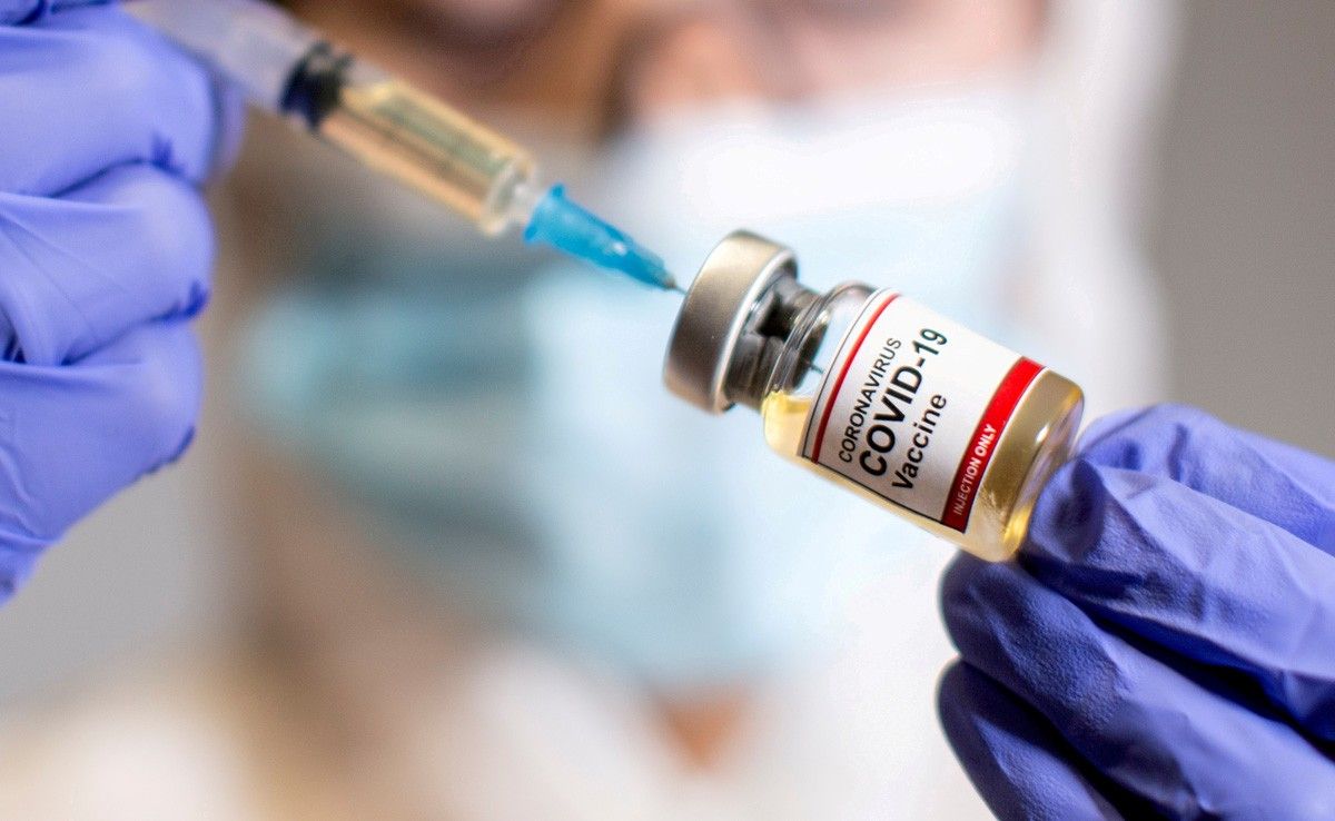 Una dona té una xeringa mèdica i una ampolla petita amb l'etiqueta «Vacuna contra el coronavirus Covid-19»