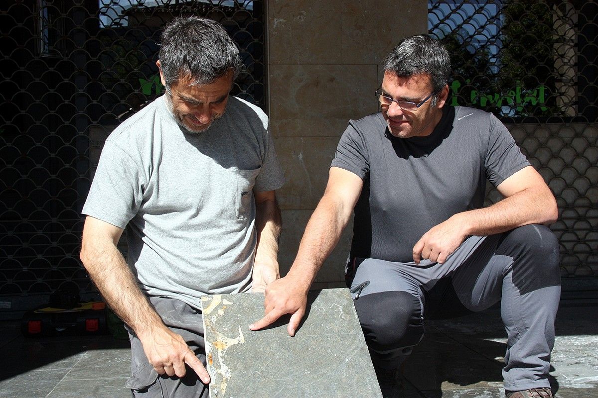 Els geòlegs Roger Mata i Jordi Ferrer, amb el fòssil del sirènid que està incrustat a les llambordes del paviment
