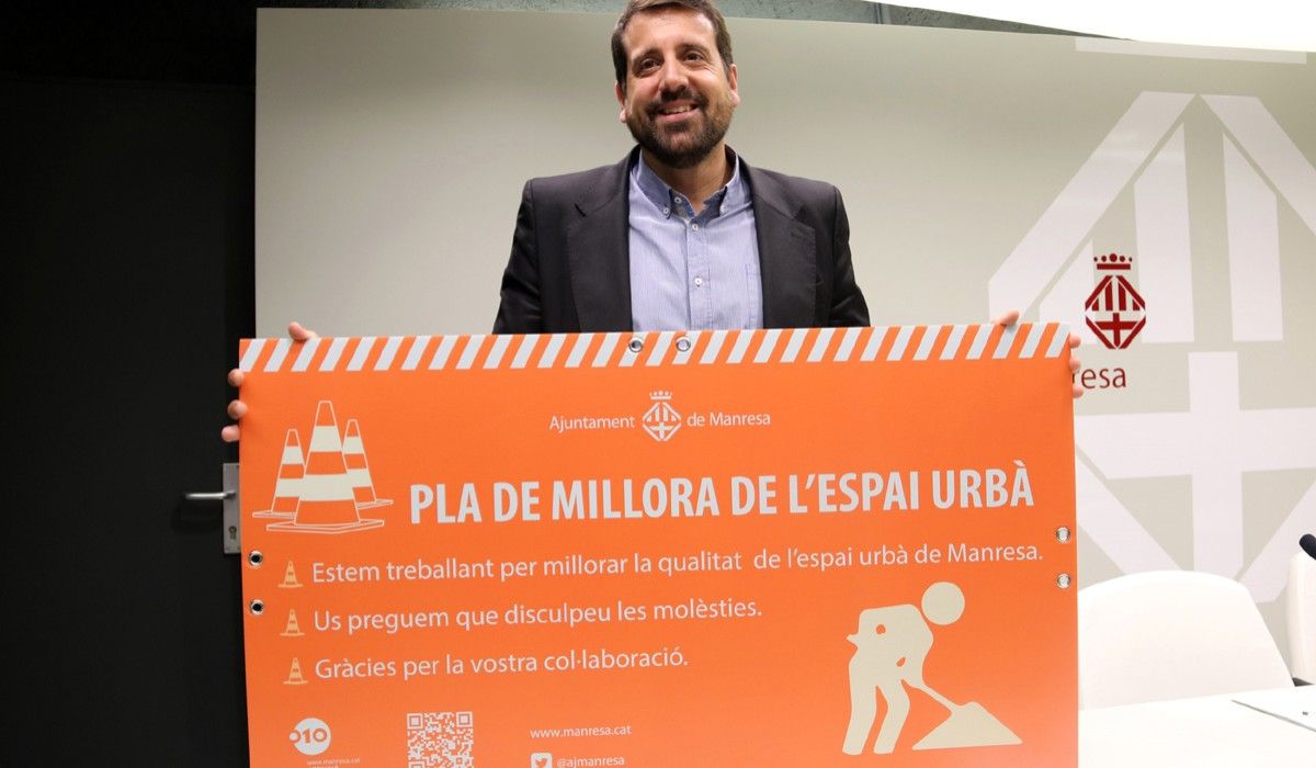 El regidor de Qualitat Urbana, Jordi Serracanta, amb un cartell on s'hi pot llegir Pla de millora de l'espai urbà