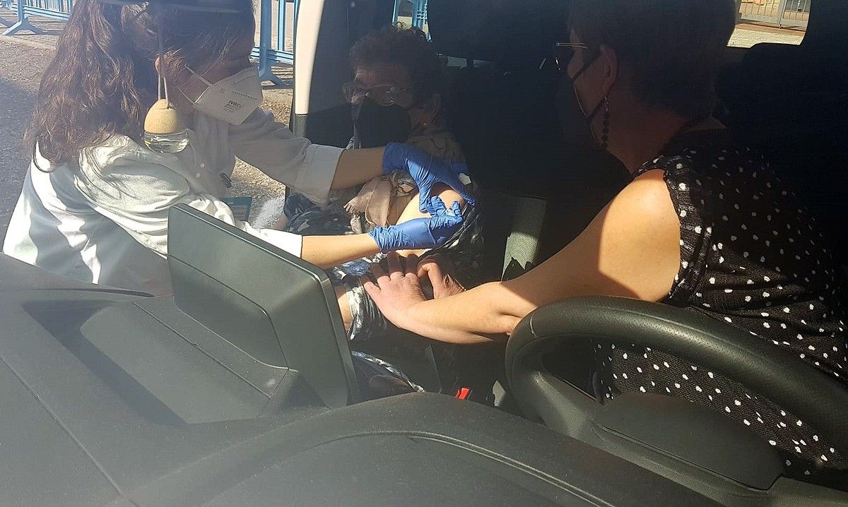 Una sanitària del CAP Artés aplica la vacuna a una dona gran a dins del cotxe