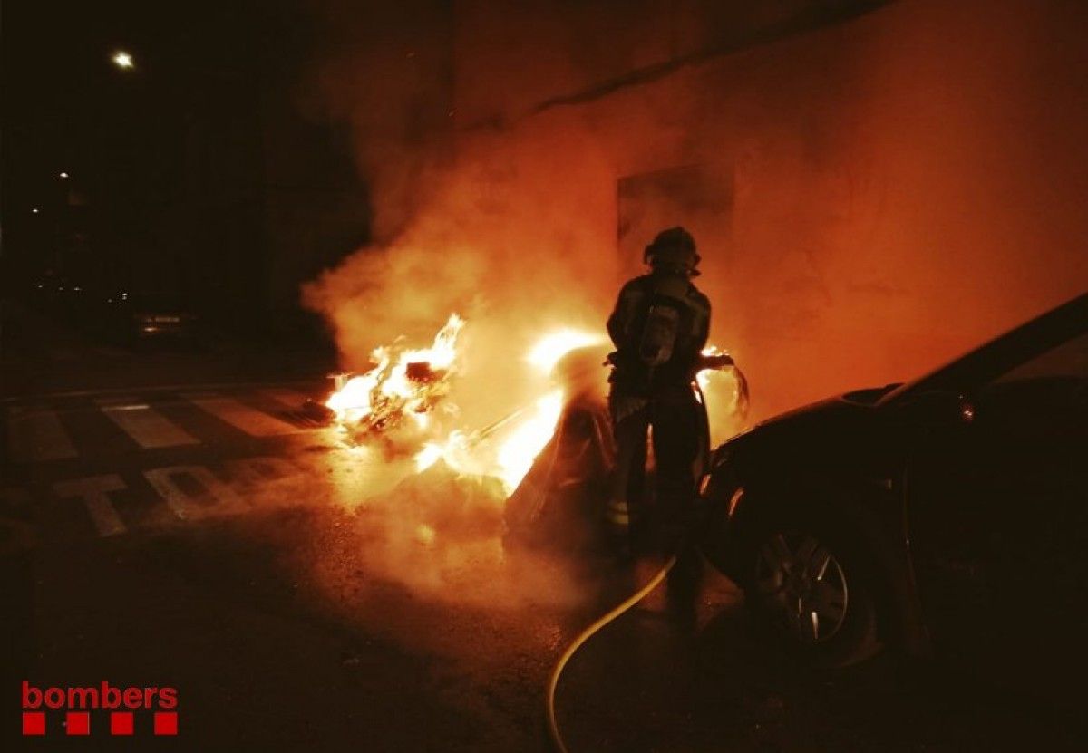 Un bomber apagant el foc originat en un contenidor, en una imatge d'arxiu