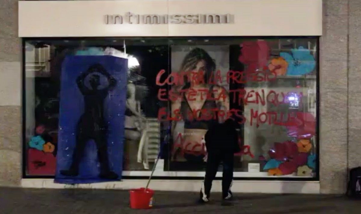 Imatge d'una membre d'Acció Lila pintant l'aparador de la botiga Intimissimi