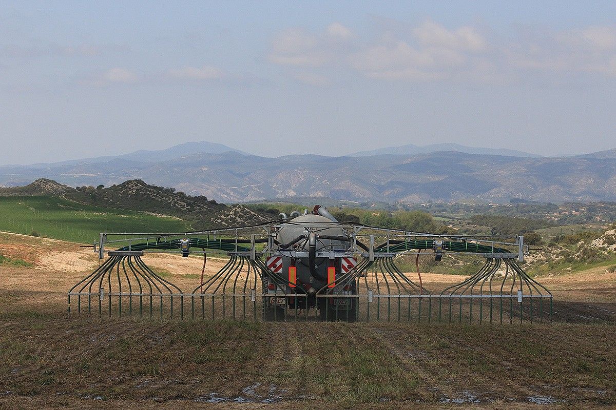 Un tractor amb cisterna aplicant purins en una explotació agrària mitjançant el sistema de ventall