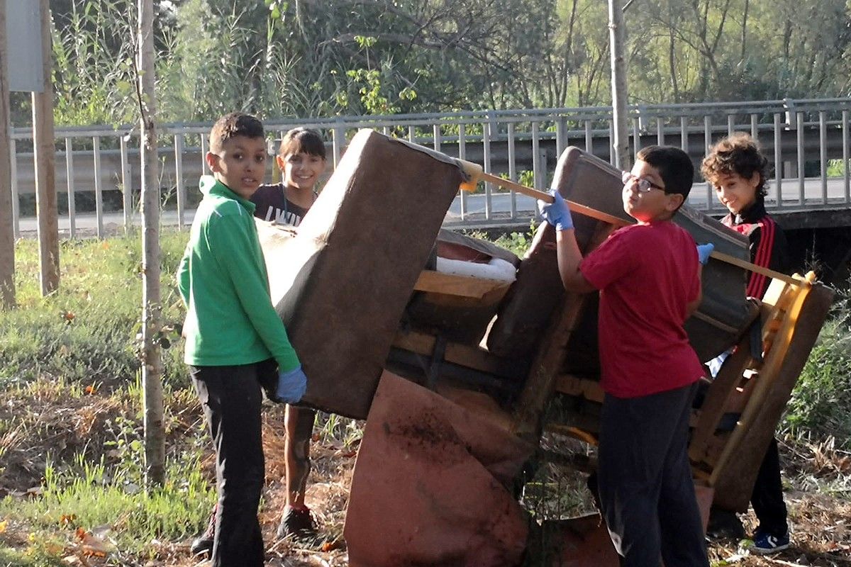 Nois que fan de voluntaris retirant mobles de la llera de la riera de Rajadell