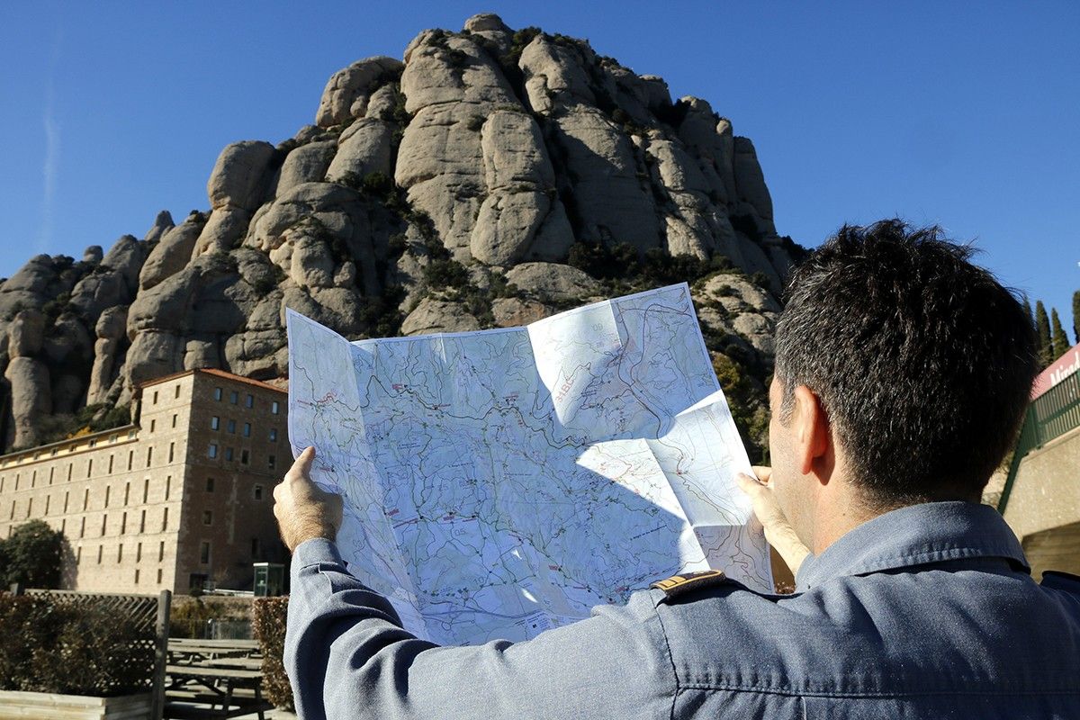 Un bomber observa el mapa cartogràfic davant de la muntanya de Montserrat