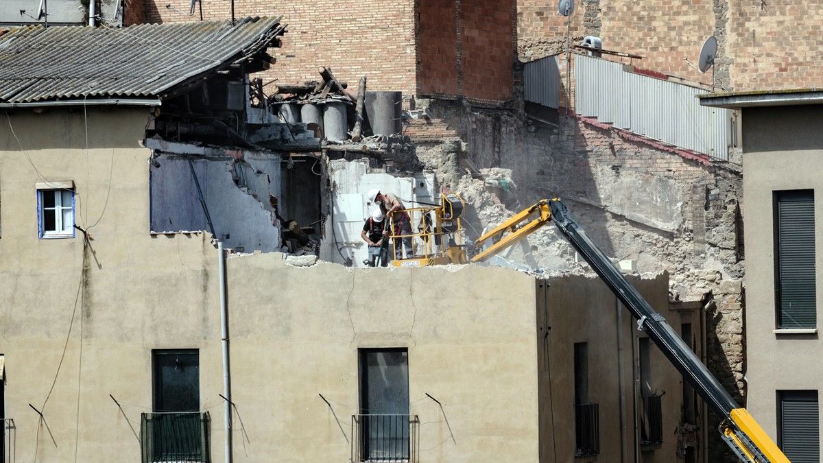 Operaris treballant des del quart pis després d'haver desmuntat la coberta de part de l'edifici