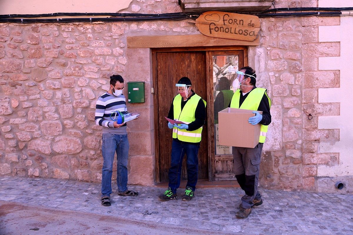 Treballadors de l'Ajuntament repartint mascaretes i pantalles protectores als propietaris del forn de Fonollosa