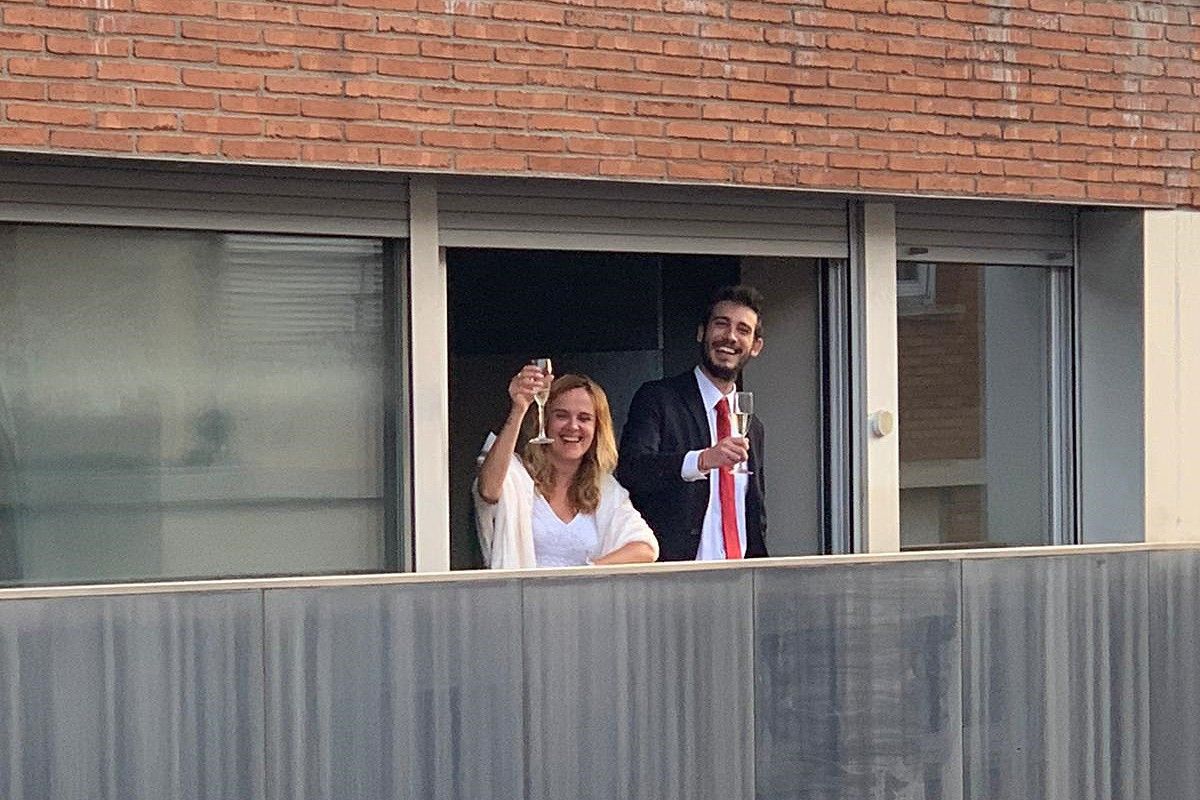 La parella de nuvis saludant els convidats des del balcó de casa seva