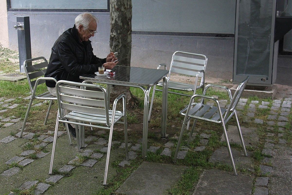 Una persona fent un cafè en una taula d'una terrassa d'un bar d'Oliana (Alt Urgell)