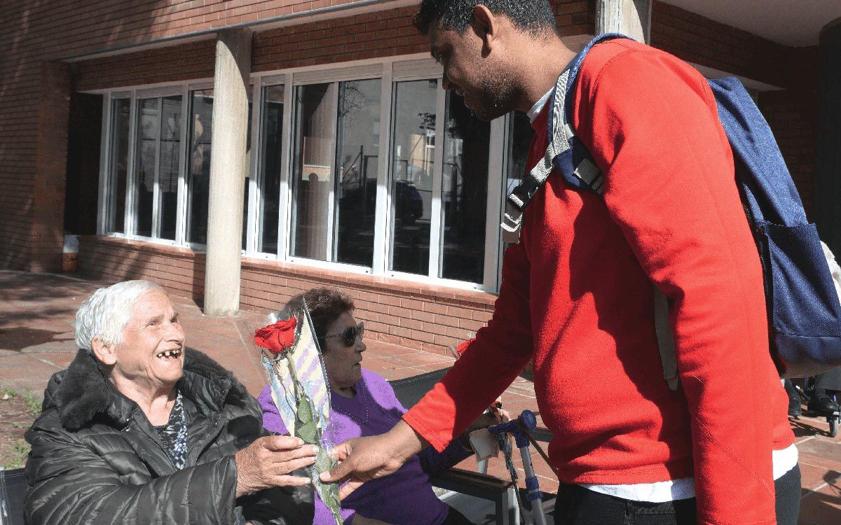 Un usuari d'Ampans lliurant una rosa a una anciana d'una residència