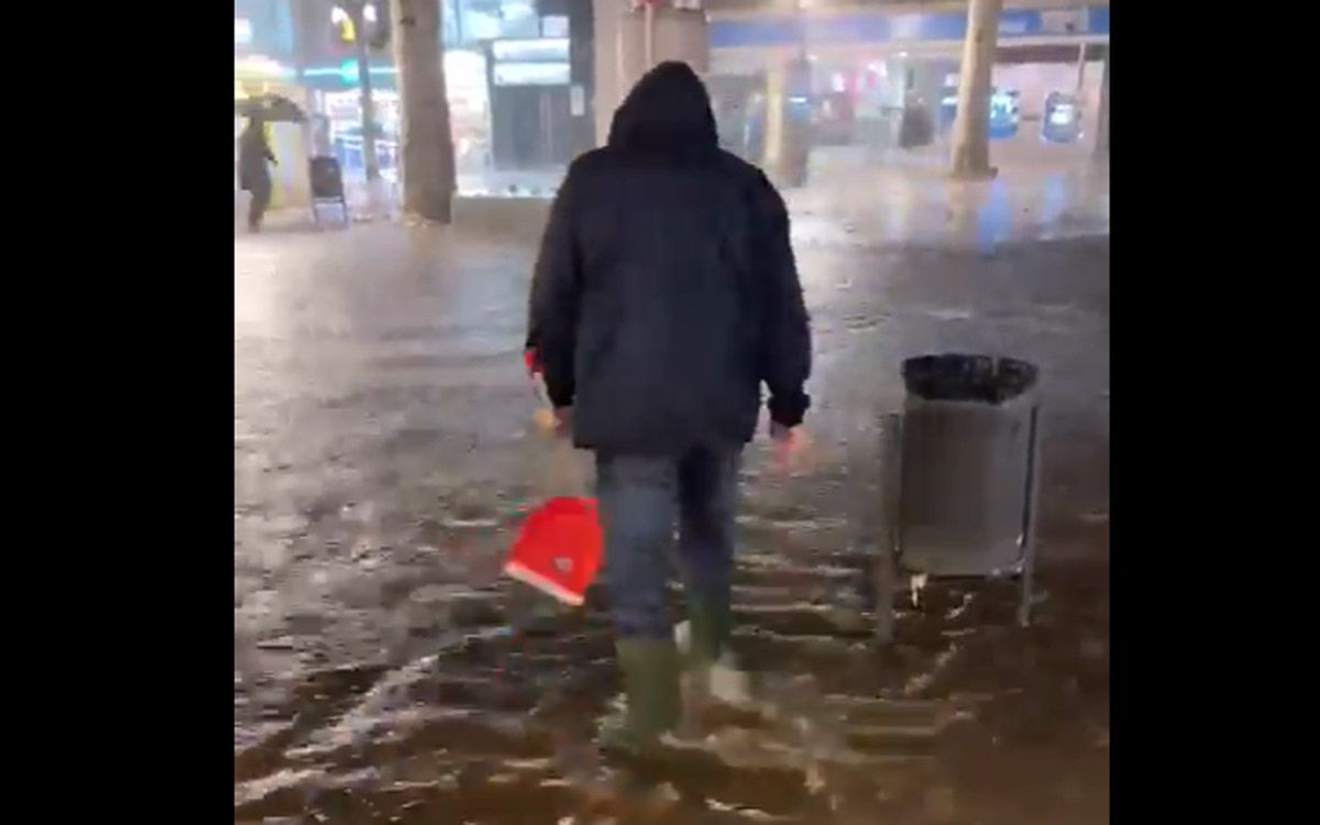 Un comerciant del carrer Guimerà intentant empènyer l'aigua cap els desguassos