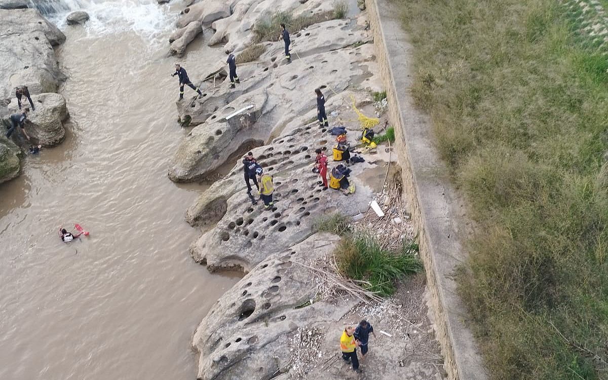 La noia, a la part inferior de la foto amb un sanitari, i els dos agents dels Mossos encara a dins de l'aigua