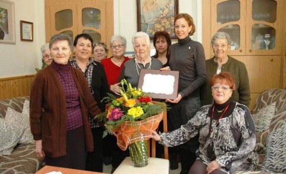 La regidora Àuria Caus entrega una placa i flors a Antònia Llanes Aiguadé.