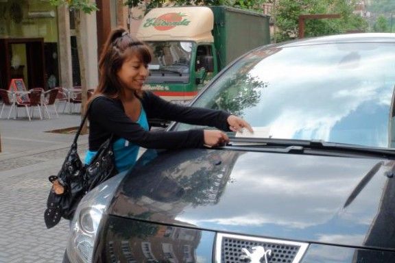 Una alumna de la Casa d'Oficis posa una multa a un vehicle mal aparcat.