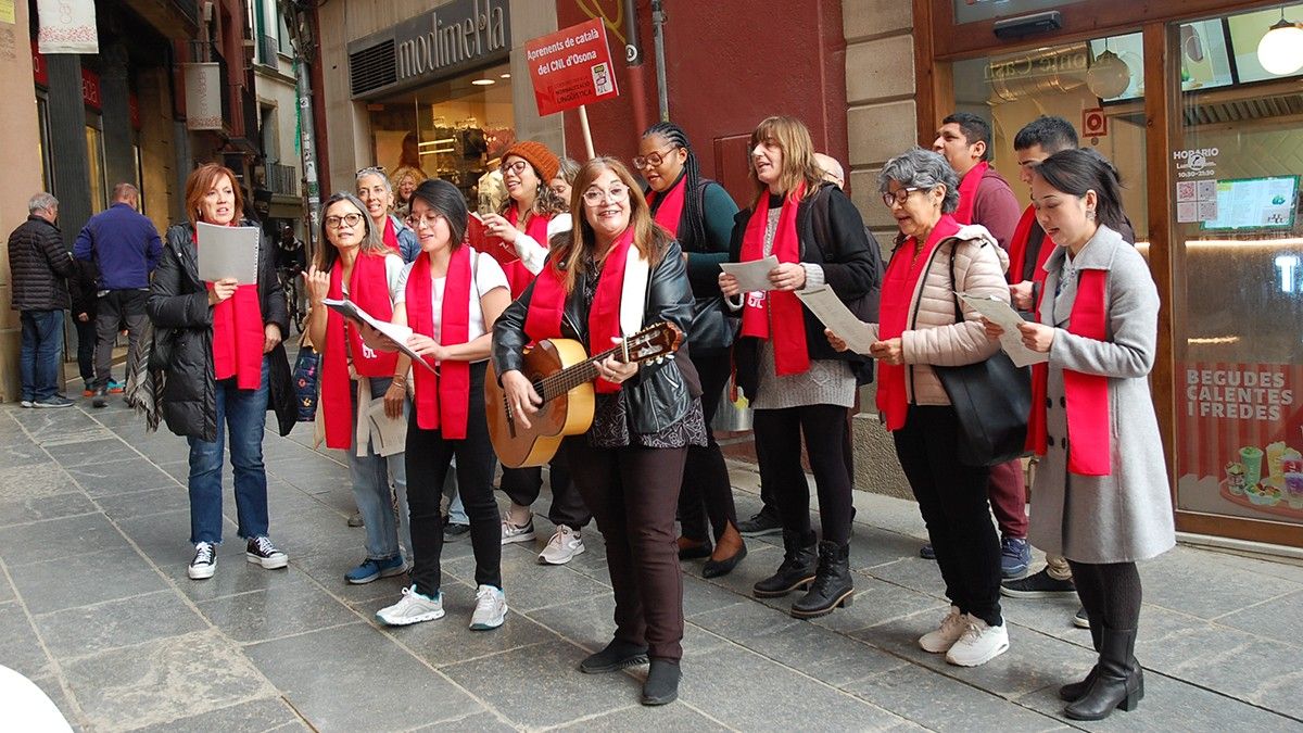Una vintena d'aprenents de català i voluntaris del CNL d'Osona cantant cançons populars i corrandes a Vic.