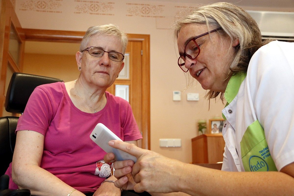 La infermera de la FADO Fina Casanovas mostra la nova 'app' a una de les usuàries del servei, Montserrat Vila