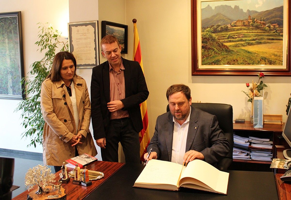 Vilagrà i Garrido mirant a Junqueras mentre signa el Llibre d'Honor de la ciutat.