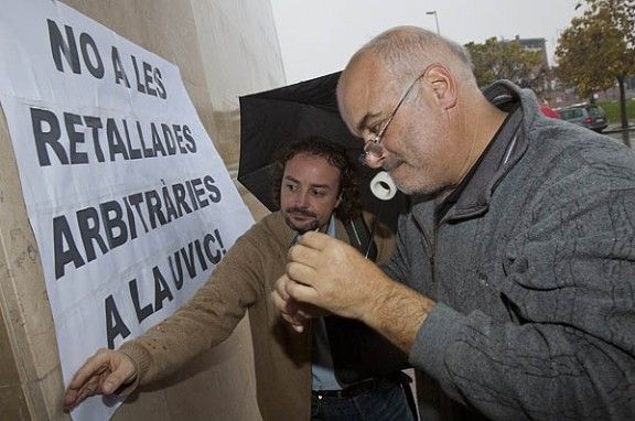 Dos dels manifestatns enganxant una pancarta ala façana de la Torre dels Frares.