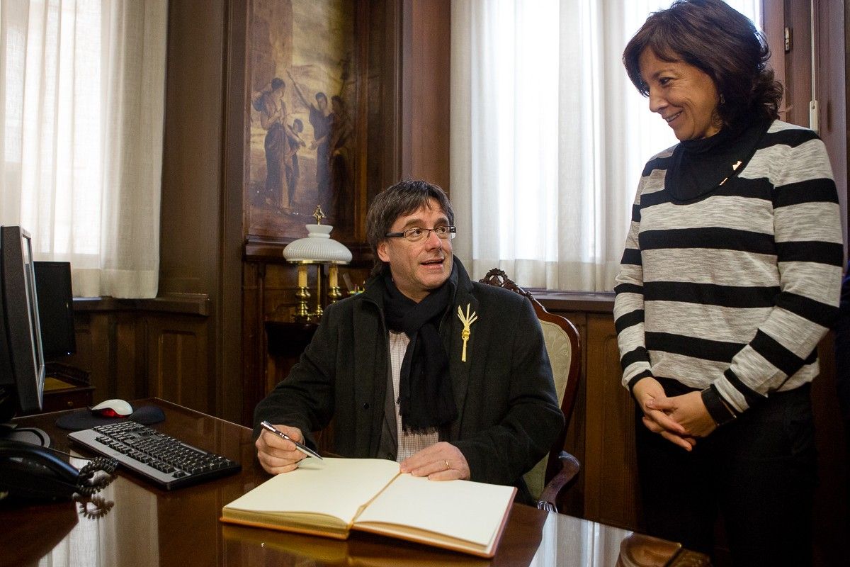 Puigdemont signant el llibre d'honor de l'Ajuntament de Vic durant la visita que va fer al Mercat del Ram, l'any 2016.