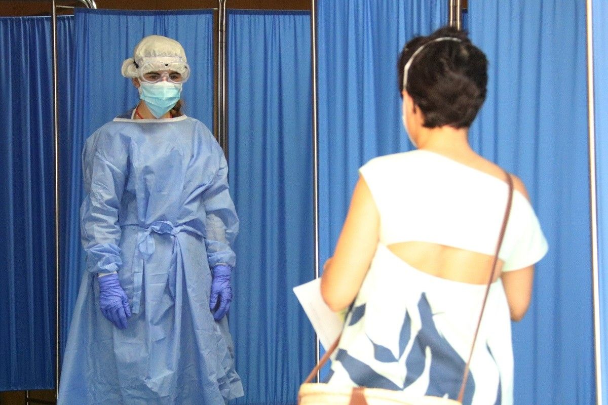 Una sanitària rebent una dona que va a fer-se una PCR.