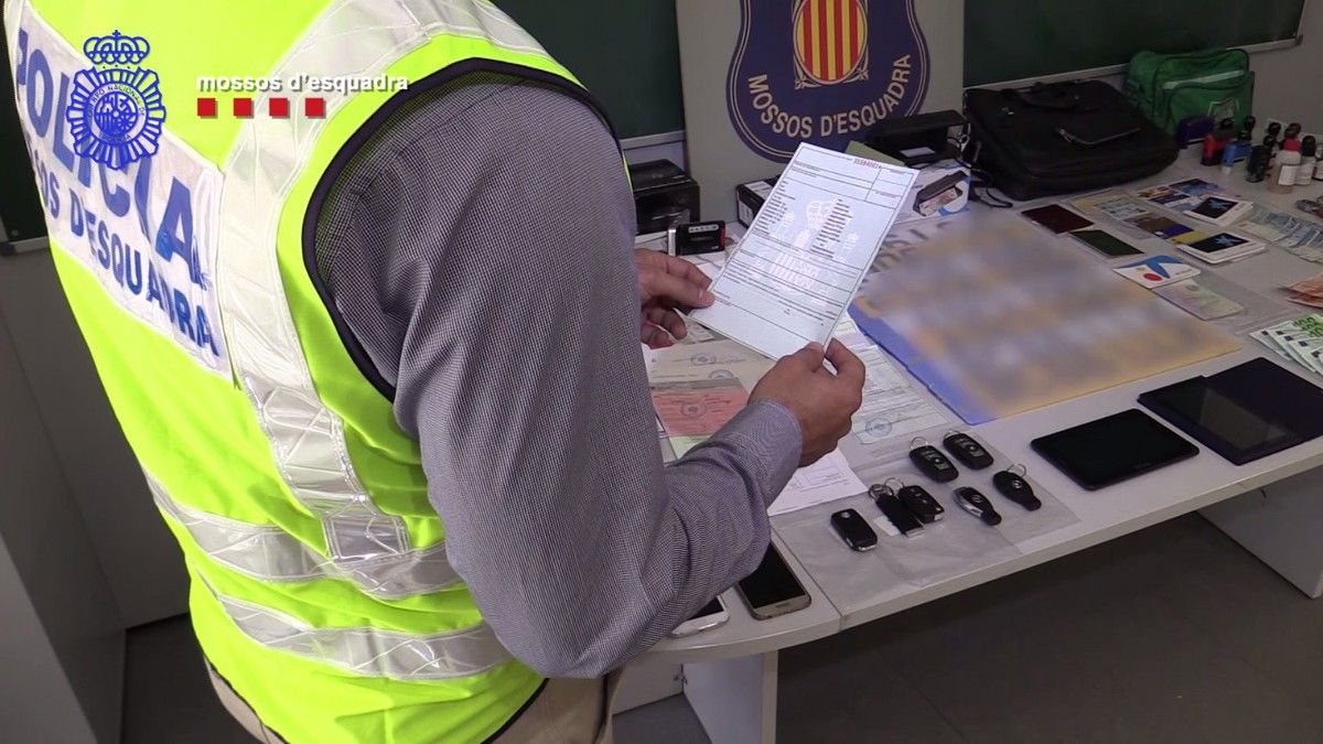 Un agent dels Mossos d'Esquadra sosté un permís de conduir, amb documentació i clauers dels vehicles intervinguts de fons