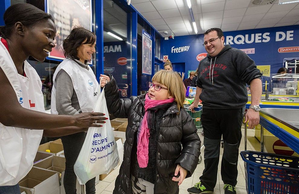 Una nena entrega una bossa plena d'aliments als voluntaris del Gran Recapte.