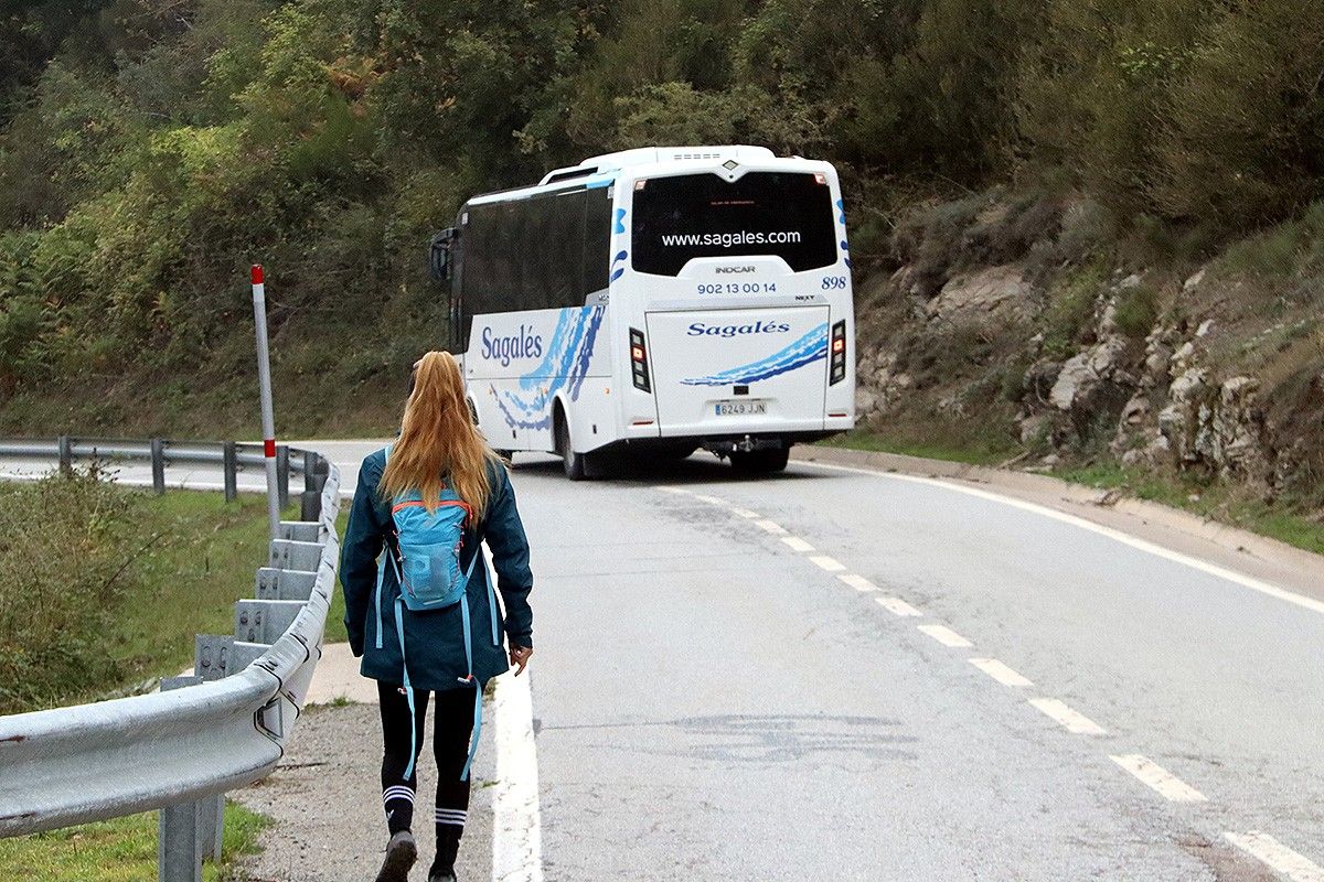 Una excursionista en primer pla i, al fons, una de les línies de bus de la prova pilot.