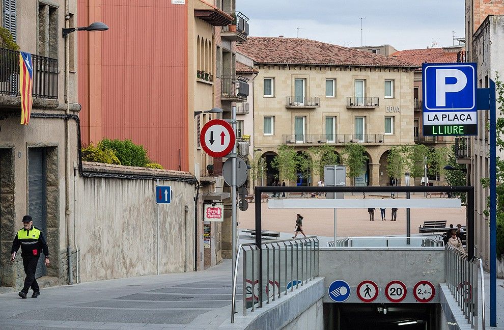 Un vigilant de la zona blava passant pel costat de l'entrada del pàrquing de la plaça Fra Bernadí.