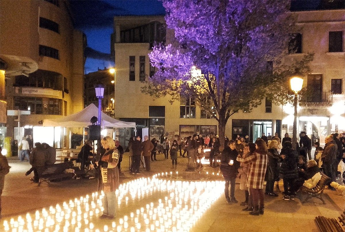 Espelmes a terra i l'om lila per recordar les víctimes de la violència masclista