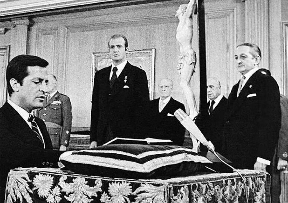 El rei mira Suárez  prometent el càrrec. A la dreta, Torcuato Fernández-Miranda.