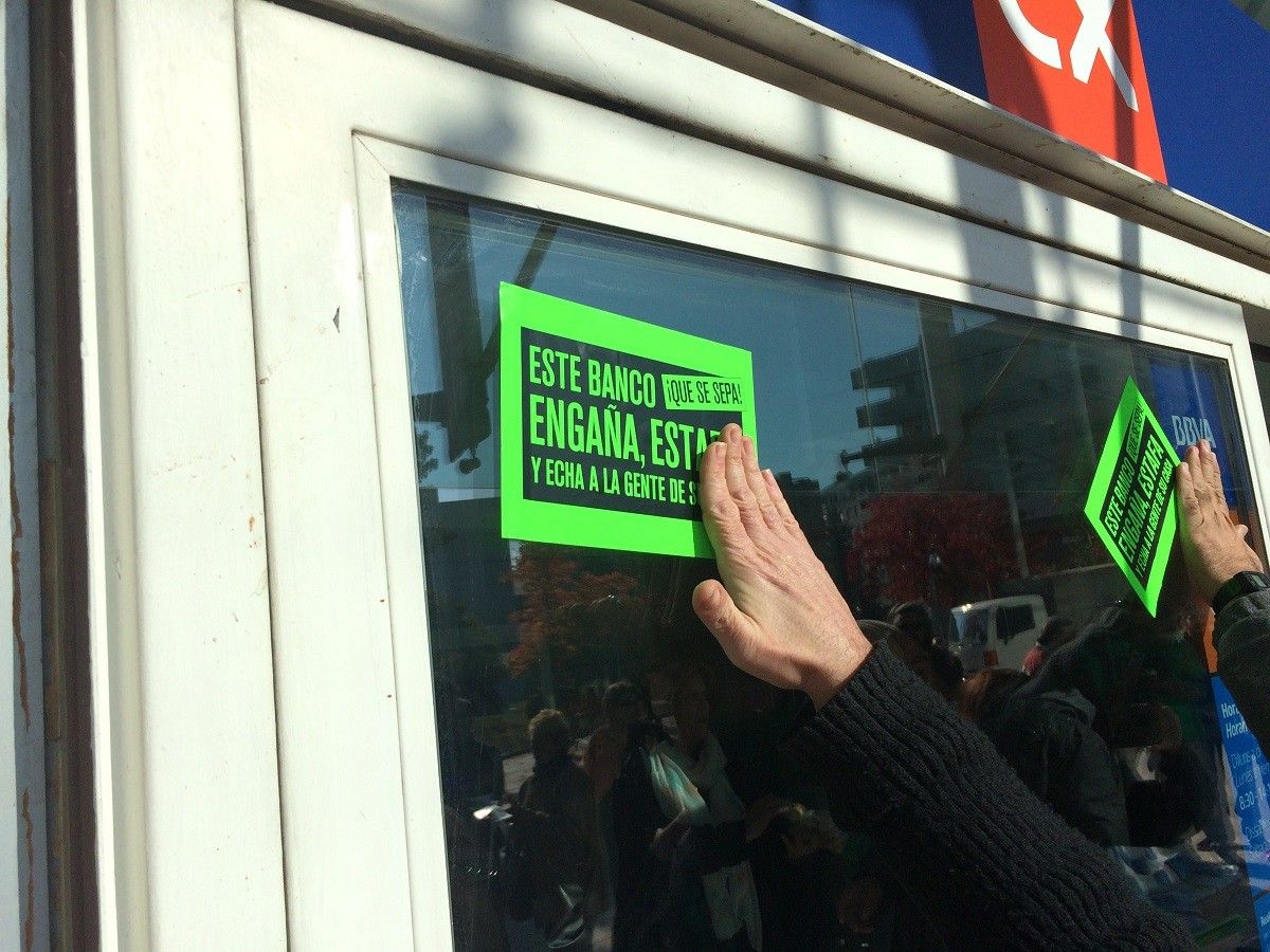 Els activistes, enganxant adhesius a la porta del banc