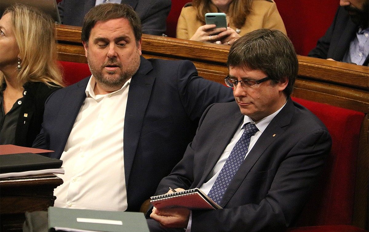 Oriol Junqueras observa com Carles Puigdemont pren notes durant el ple del Parlament