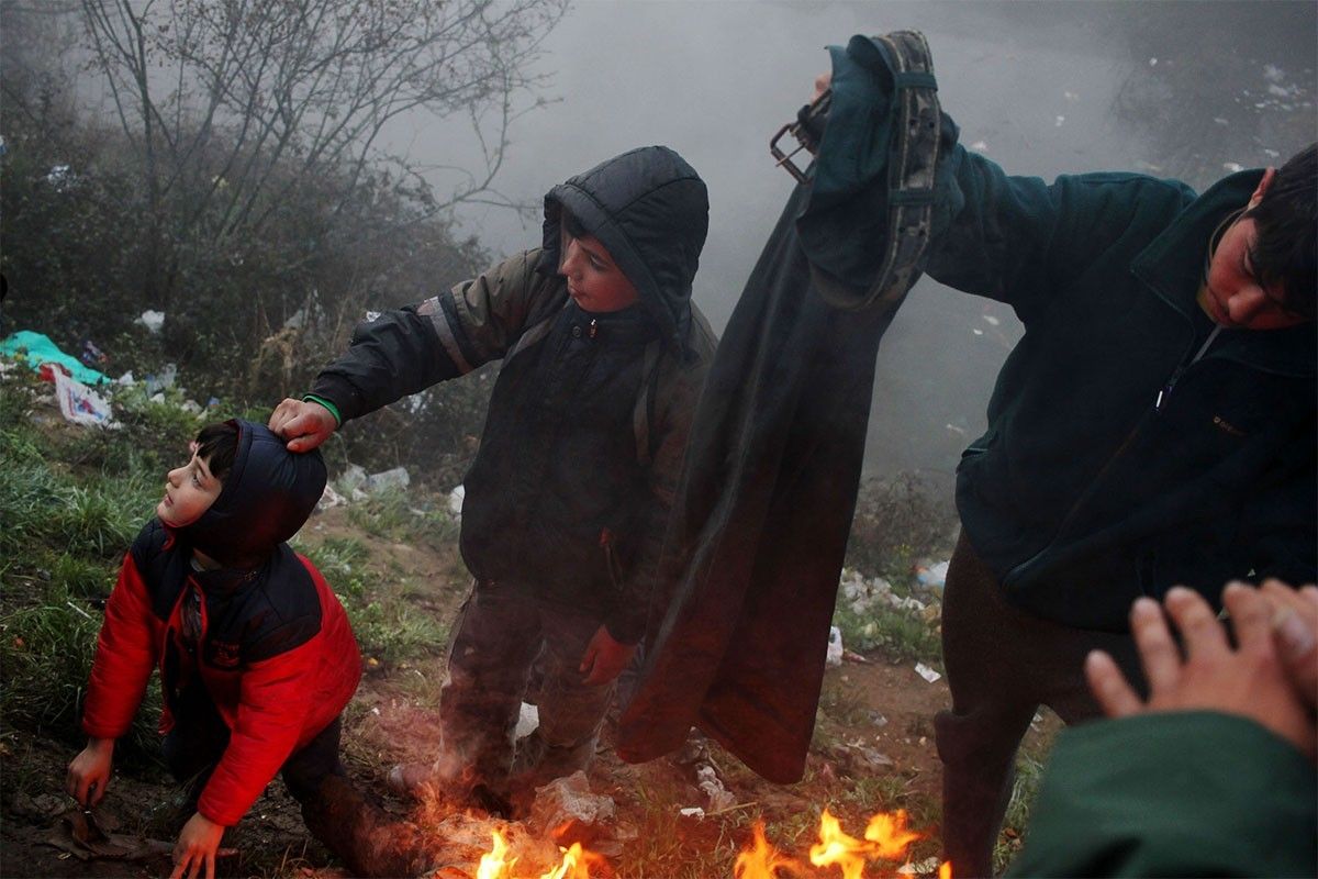 Uns nens sirians, escalfant-se a l'entorn del camp de refugiats d'Idomeni, a Grècia