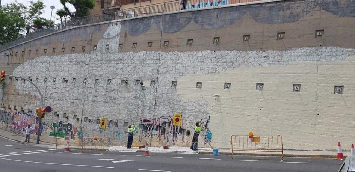 Operaris esborren el mural del tauró capitalista