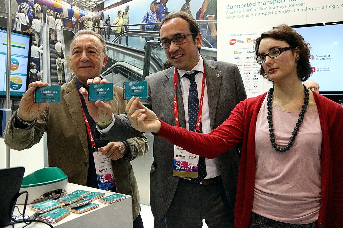 Antoni Poveda, Josep Rull i Mercedes Vidal mostren exemplars de la T-Mobilitat durant un acte al MWC aquest dimecres